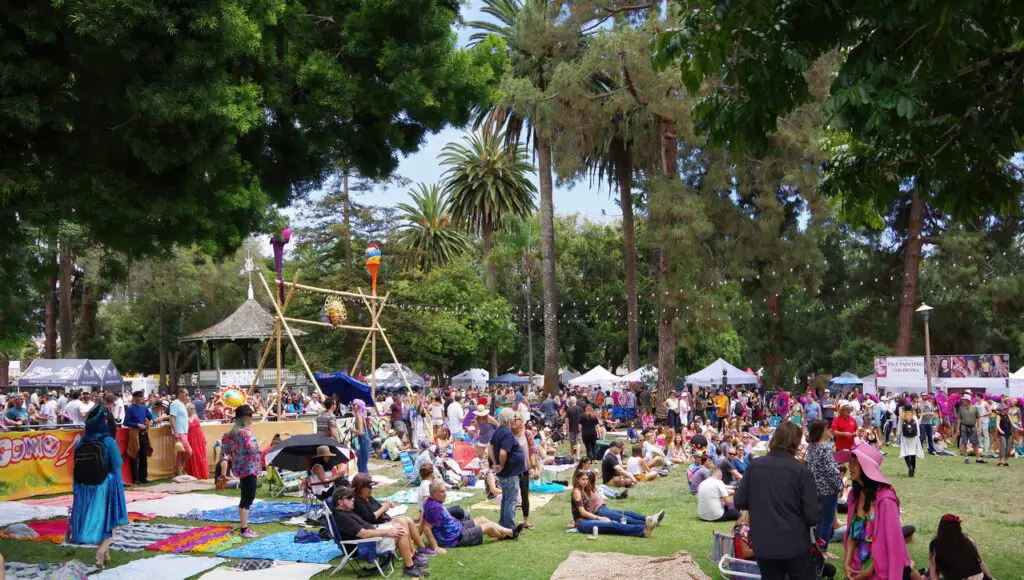 Outdoor festival with crowd and tents in park.